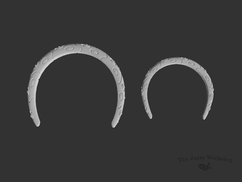 May include: Two white plastic headbands with a decorative eye pattern. The headbands are different sizes.