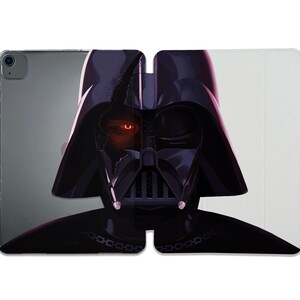 May include: A black and purple iPad case featuring a stylized illustration of Darth Vader. The artwork depicts Vader's helmet with a glowing orange eye and a partially damaged mask. The case is open, revealing the iPad.