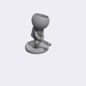 May include: A gray, stylized figurine of a person holding a small, gray object. The figurine is standing on a round, gray base.
