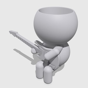 Könnte beinhalten: Ein grauer Pflanztopf im Cartoon-Stil in Form einer Figur, die E-Gitarre spielt. Die Figur hat einen großen, runden Kopf und eine ausgehöhlte Oberseite zum Bepflanzen. Die Gitarre ist mit Hals und Saiten detailliert.