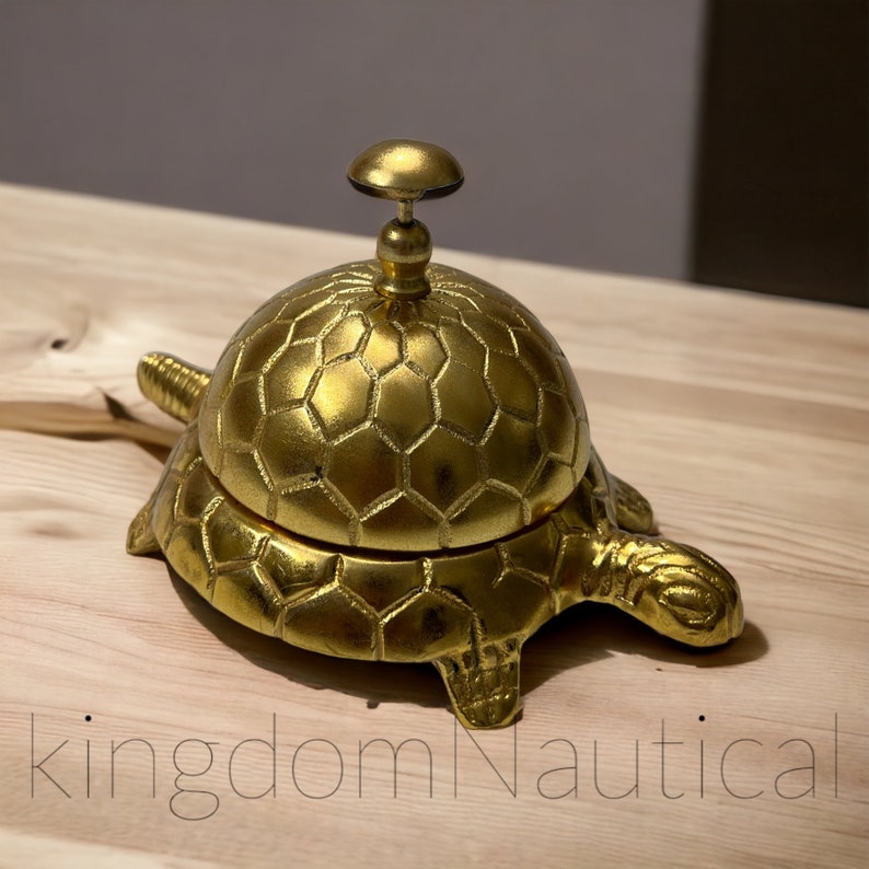 Brass turtle-shaped service bell with gold finish on wood surface