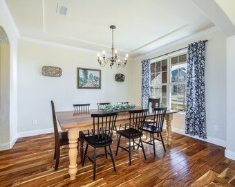 May include: A wooden dining table with six black chairs sits in a room with hardwood floors. The table has a light wood finish and the chairs have black wooden seats and backs. A chandelier hangs from the ceiling above the table.