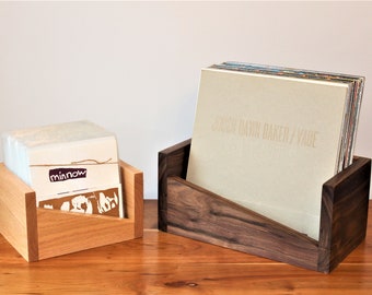 May include: Two wooden record storage boxes. The box on the left is made of light wood and has the word "minnow" printed on the front. The box on the right is made of dark wood and has the text "JOUJOU DAWN BAKER / VADE" printed on the front.