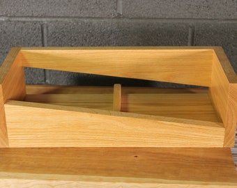 May include: A wooden box with a sloping shelf inside. The box is made of light wood and has a natural finish.