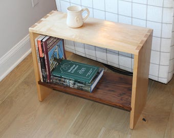 May include: A light wood end table with a walnut shelf. The table has a simple design with a rectangular top and a single shelf. There are three books on the shelf, including one with the title "Modeling in Practice".