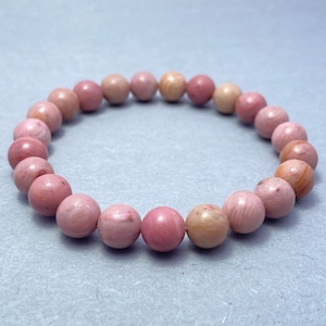 Op de afbeelding: Een armband van roze en witte edelstenen met ronde kralen.