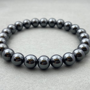 Può includere: Un braccialetto di perline di ematite nera con perline rotonde lucide.