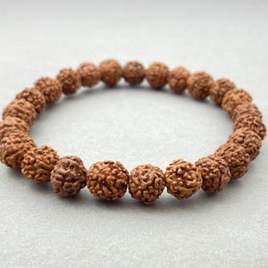 May include: A brown beaded bracelet made of natural seed beads. The bracelet is made of a single strand of beads and is approximately 7 inches in length.