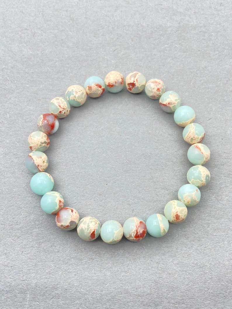 May include: A light blue and brown speckled stone bracelet with 18 beads.
