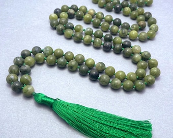 May include: A long strand of round, mottled olive-green stone beads strung on a vibrant green cord. The necklace features a prominent, bright green silk tassel attached at the bottom, with the beads arranged in a continuous loop.