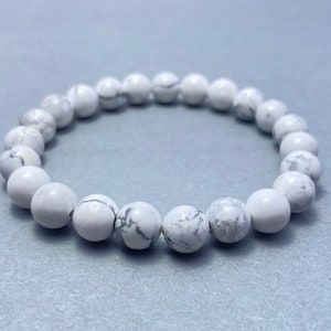 Könnte beinhalten: Ein weißes Howlith-Perlenarmband mit schlichtem Design. Die Perlen sind rund und glatt, und das Armband ist aus Naturstein.