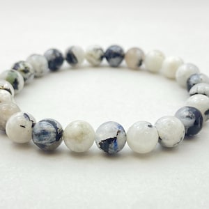 以下が含まれることがあります： 丸いビーズでできた白と黒の宝石のブレスレット。ビーズには斑点模様があります。