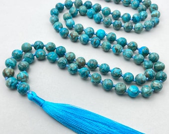 May include: A turquoise blue mala necklace with a tassel. The beads are round and have a marbled pattern.
