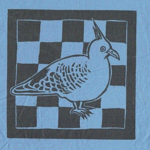 May include: A light blue fabric featuring a screen-printed design. The design shows a white bird with a crest, standing on a checkered background framed by a dark grey border. The bird is centrally positioned.