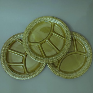 Può includere: Tre piatti divisi in ceramica verde oliva con un bordo decorativo. I piatti sono impilati uno sopra l'altro.
