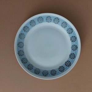 May include: A white ceramic plate with a blue and grey floral pattern around the rim.