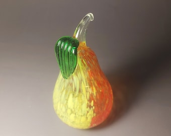 May include: A glass pear figurine with a green leaf, yellow and orange speckled glass.