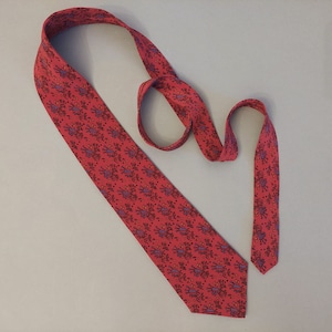 May include: A red silk tie with a floral pattern in shades of purple, orange, and black.