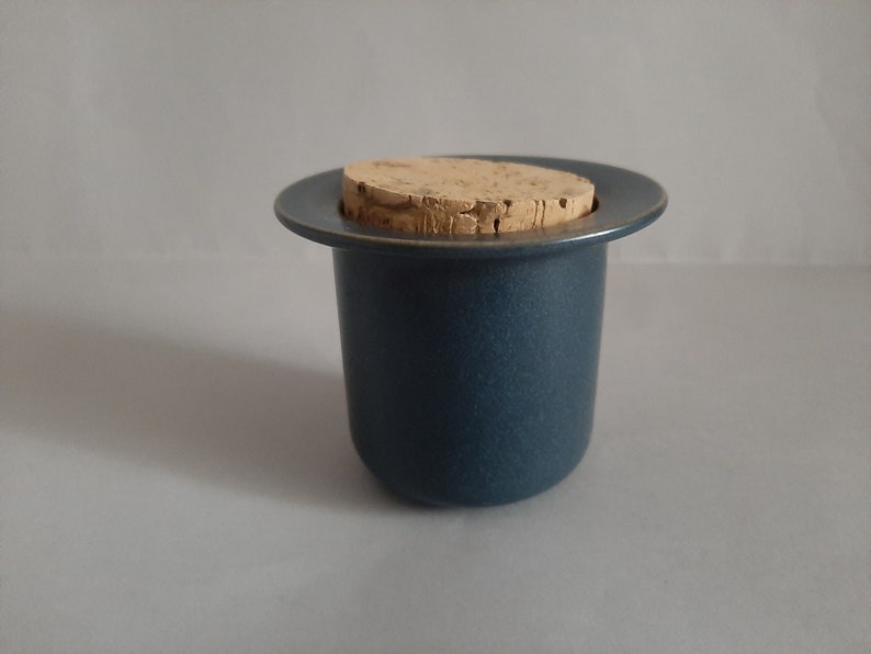 May include: A dark blue ceramic jar with a cork lid. The jar has a wide rim and a smooth, textured surface.
