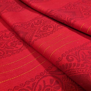 May include: Red fabric with a gold thread woven into the fabric. The fabric has a repeating pattern of stylized flowers and leaves.
