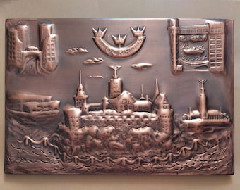 May include: A copper-coloured metal plaque depicting a stylised cityscape of Stockholm, Sweden. The plaque features three crowns above the word "STOCKHOLM" and a detailed depiction of the city's skyline, including buildings, water, and a bridge.
