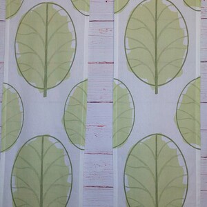 May include: Two white fabric panels with a repeating pattern of large, light green leaf shapes. Each leaf has a dark green outline and a central vein. The background is a light, neutral color.
