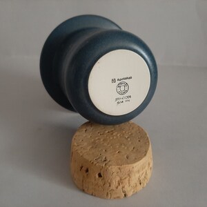 May include: A blue ceramic cup with a white bottom. The bottom has the text "Agapetus" and a logo with the text "STHLM-GDS" and "SWEDEN".