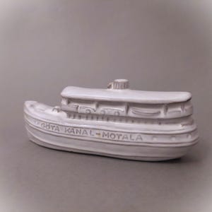 以下が含まれることがあります： 「GÖTA KANAL - MOTALA」と刻まれた白い陶器製のボートの置物です。