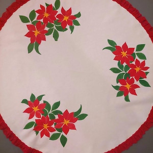 May include: White round tablecloth with red crocheted trim and a painted design of red poinsettia flowers with green leaves.