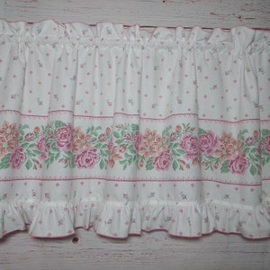 May include: White valance with a pink and green floral pattern. The valance has a ruffled bottom edge and a pink trim.