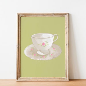 May include: A framed illustration of a white teacup and saucer with a floral design. The teacup and saucer are on a green background.