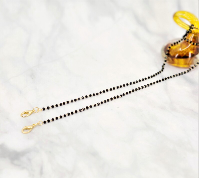 K&ouml;nnte beinhalten: Eine schwarze Perlenkette mit goldenen Verschl&uuml;ssen. Die Kette besteht aus kleinen, runden Perlen und ist etwa 60 cm lang.
