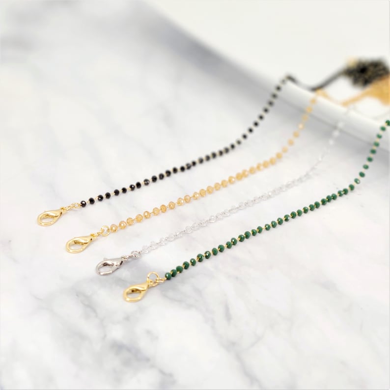 K&ouml;nnte beinhalten: Vier Perlenketten mit goldenen Verschl&uuml;ssen. Die Ketten sind schwarz, gold, silber und gr&uuml;n.