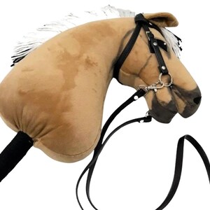 Pu&ograve; includere: Una testa di cavallo di peluche marrone con una criniera bianca e redini in pelle nera. La testa del cavallo &egrave; attaccata a un bastone di legno con un'impugnatura in tessuto nero.