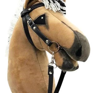Pu&ograve; includere: Una testa di cavallo di peluche marrone e nero con una briglia e redini in pelle nera. Il cavallo ha una criniera e una coda bianche.