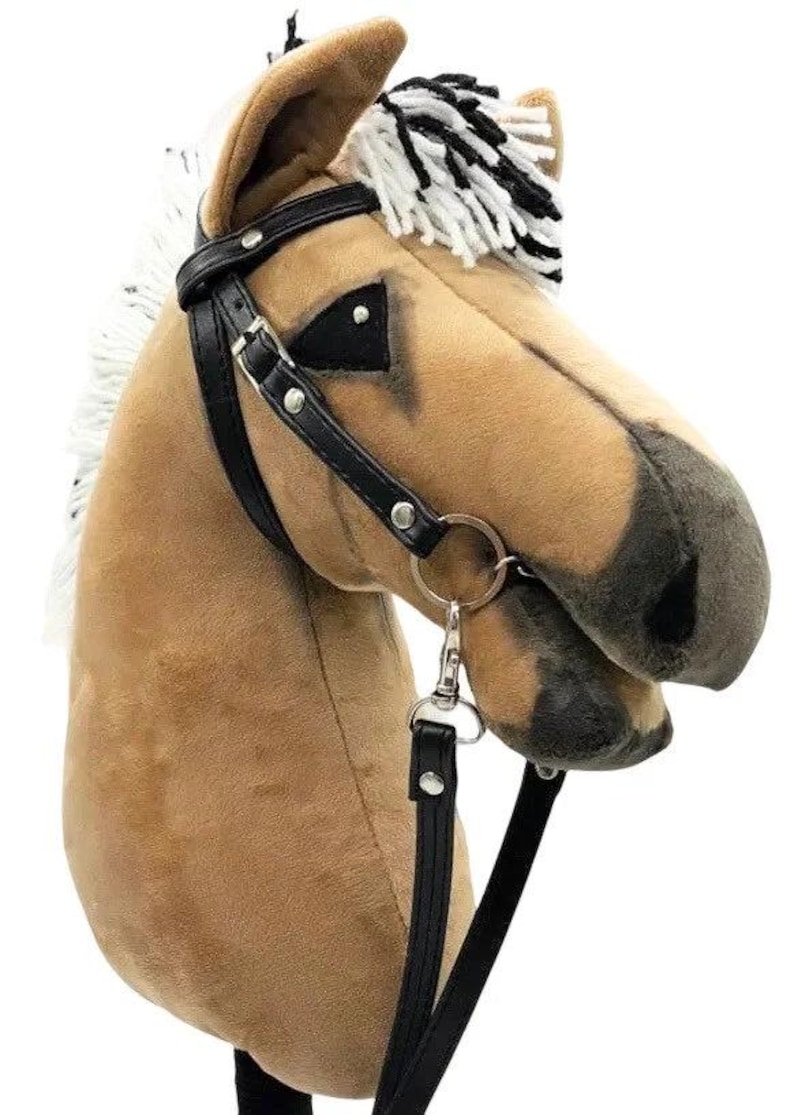 Pu&ograve; includere: Una testa di cavallo di peluche marrone e nero con una briglia e redini in pelle nera. Il cavallo ha una criniera e una coda bianche.