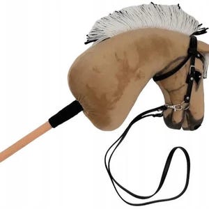 Pu&ograve; includere: Una testa di cavallo di peluche marrone e bianca con una briglia e redini nere. La testa del cavallo &egrave; attaccata a un bastone di legno.