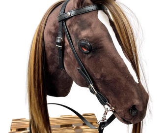 Può includere: Testa di cavallo marrone e bianca con una briglia e redini in pelle nera. La testa del cavallo è montata su una cassa di legno.