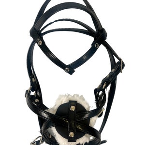 Pode incluir: Focinho de couro preto com forro de pele branca e correias ajust&aacute;veis. O focinho tem uma barra de metal que se conecta &agrave;s correas.
