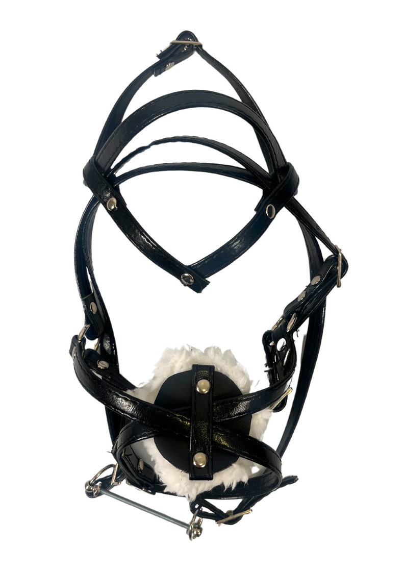 Pode incluir: Focinho de couro preto com forro de pele branca e correias ajust&aacute;veis. O focinho tem uma barra de metal que se conecta &agrave;s correas.