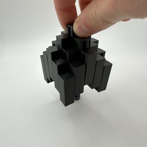 May include: A black 3D printed puzzle made of interlocking pieces in the shape of a pyramid.