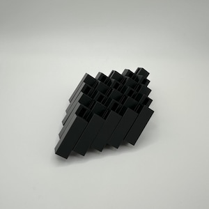 May include: A black geometric sculpture made of stacked rectangular blocks. The sculpture is abstract and modern in style.