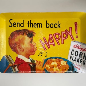 Op de afbeelding: Gele rechthoekige dienblad met een vintage Kellogg's Corn Flakes-advertentie. De dienblad toont een jongen die muzieknoten blaast, de woorden "Send them back HAPPY!" en een doos Kellogg's Corn Flakes.