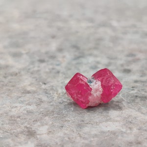 May include: A cluster of pink, translucent crystals with a slightly rough texture. The crystals are arranged in a loose, natural formation.