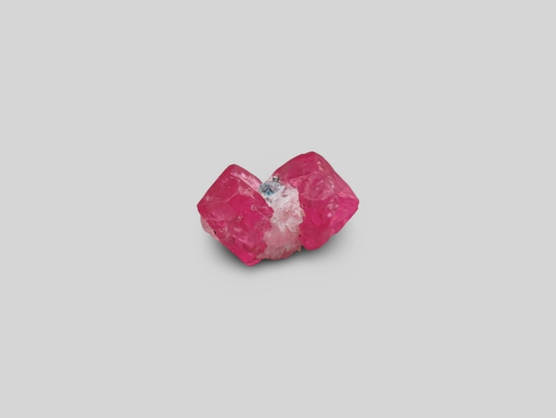 May include: A cluster of pink, red, and white crystals. The crystals are translucent and have a glassy luster. The crystals are arranged in a cluster, with some of the crystals overlapping each other.