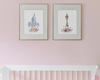 May include: Two framed prints of Disney castles with floral accents. The print on the left features Cinderella's castle in blue and white with pink, yellow, and green flowers. The print on the right features Rapunzel's tower in green with purple, pink, and green flowers.