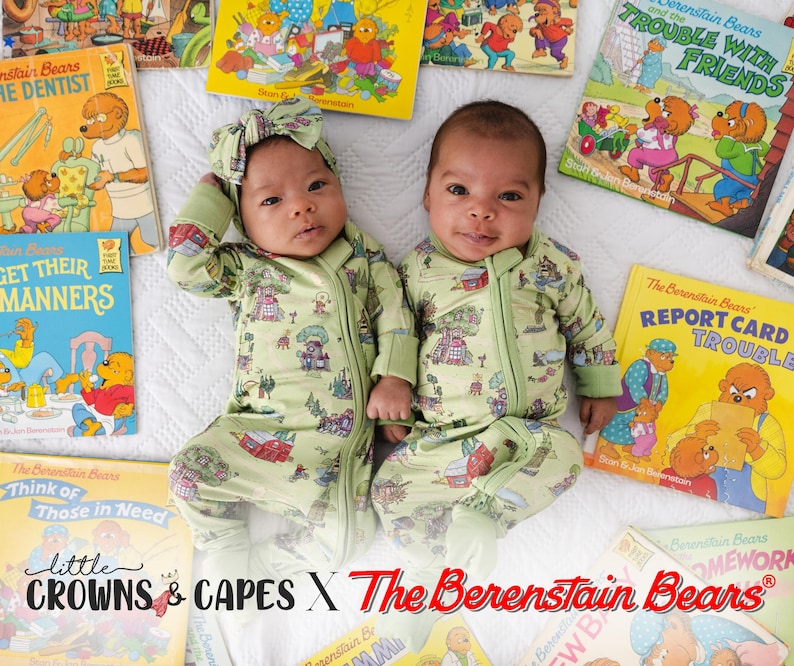 May include: Two babies in light green Berenstain Bears print onesies, with matching headbands, lying amongst children's books. The onesies have a zip closure. The books display colourful illustrations and titles such as "The Dentist" and "Trouble with Friends."
