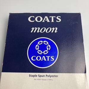 May include: A navy blue box of Coats Moon staple spun polyester thread. The box features the brand name in white, with a circular logo and the text "Staple Spun Polyester". The box also includes the art number and the thread length.