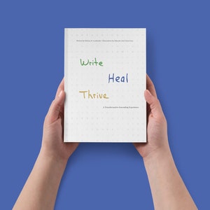 Puede incluir: Un diario blanco con las palabras "Write", "Heal" y "Thrive" escritas en diferentes colores en la portada. El diario es una experiencia de diario transformadora.