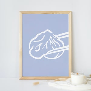 May include: A framed print with a light blue background and a white illustration of a dumpling being picked up with chopsticks.
